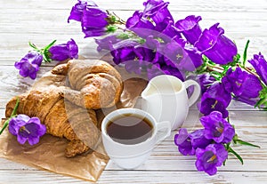 Cup of coffee, croissants, milk jar and lilac flowers