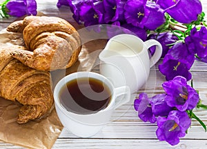 Cup of coffee, croissants, milk jar and lilac flowers