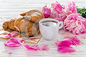 Cup of coffee, croissants, milk jar and peonies flowers