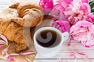 Cup of coffee, croissants, milk jar and peonies flowers