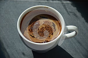 A cup of coffee with crumbles on the surface