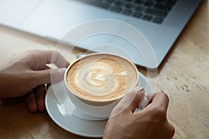 A cup of coffee on desk, Cup of coffee in hand, Men hand hold mug of latte coffee, Close up concept