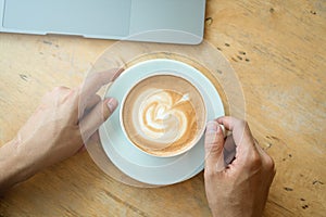 A cup of coffee on desk, Cup of coffee in hand, Men hand hold mug of latte coffee, Close up concept