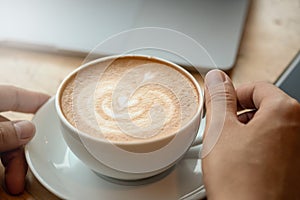 A cup of coffee on desk, Cup of coffee in hand, Men hand hold mug of latte coffee, Close up concept