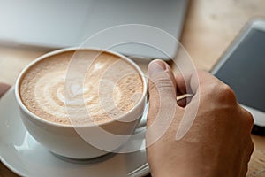 A cup of coffee on desk, Cup of coffee in hand, Men hand hold mug of latte coffee, Close up concept