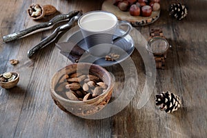 Cup of coffee, different kinds of nuts, walnut, hazelnuts, almonds on old wooden table boards, edible seed kernels, food concept,