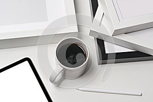 Cup of coffee, digital tablet and empty picture frames on white background.