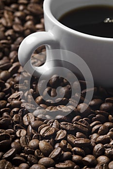 Cup of coffee drink sitting on a bed of roasted coffee beans background.