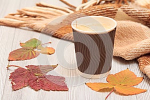 Cup of coffee, dry leaves and a plaid in an autumn still llife