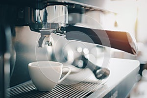 A cup of coffee is on the espresso machine,Coffee maker
