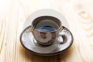 Cup of Coffee espresso on saucer on wooden table background. Sunny morning breakfast concept.