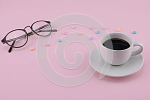 A cup of coffee and eyeglasses decorate with pastel heart pattern