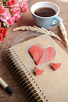 Cup of coffee with flower and red heart shape paper and notepad
