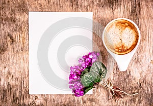 Cup of coffee and flowers. Empty sheet of paper and cup of coffee on the table.