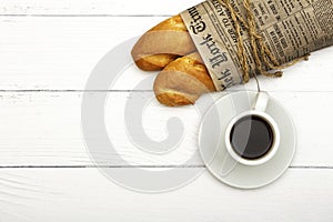 A cup of coffee, fresh bread, toast on a white woody background. Morning breakfast fresh bread with a cup of coffee. View from abo