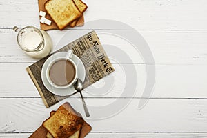 A cup of coffee, fresh bread, toast on a white woody background. Morning breakfast fresh bread with a cup of coffee. View from abo