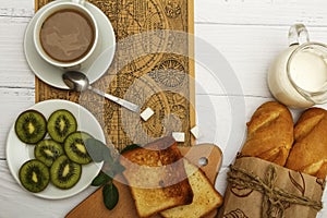 A cup of coffee, fresh bread, toast on a white woody background. Morning breakfast fresh bread with a cup of coffee. View from abo