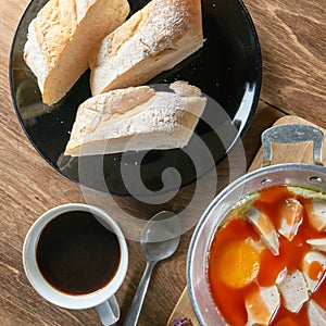 A cup of coffee with fresh sliced Italian bread and panned egg a