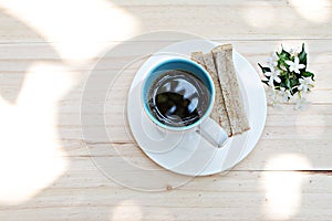 Cup of coffee, fresh tuna sandwich and white flowers on wood background