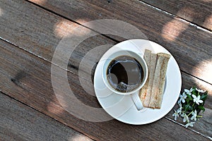 Cup of coffee, fresh tuna sandwich and white flowers on wood background