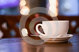 a cup of coffee with froth (raf  cappuccino  latte) on a table in a cafe against a background of garland lights