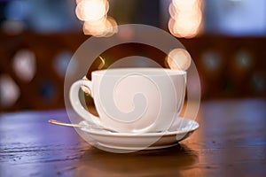 a cup of coffee with froth (raf  cappuccino  latte) on a table in a cafe against a background of garland lights