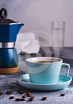 A cup of coffee and Geezer coffee maker under blurred bokeh background