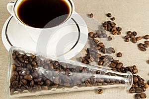 Cup and coffee grains in a glass jar on linen napkin