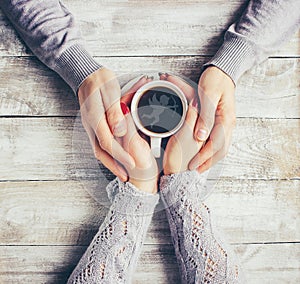 A cup of coffee in the hands of lovers. Silhouette in a cup.