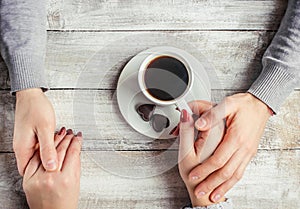 A cup of coffee in the hands of lovers. Silhouette in a cup.