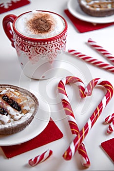 Cup of coffee with heart shape christmas candy and mini cakes.