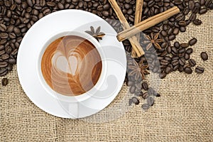 Cup of coffee with heart shape in foam on hessian background