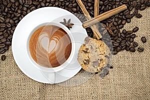 Cup of coffee with heart shape in foam on hessian background