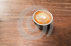 Cup of coffee with heart shape latte art on wood table