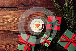 Cup of coffee and heart shape next to gift boxes on wooden table