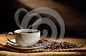 Cup of coffee with heart shape smoke and coffee beans on burlap sack on old wooden background