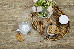 cup coffee with homemade chocolate chip cookies with honey jar and roses flowers on wood table