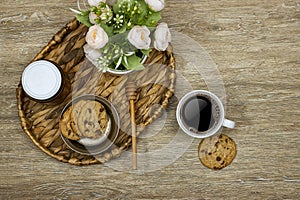 cup coffee with homemade chocolate chip cookies with honey jar and roses flowers on wood table