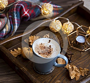 Cup of coffee or hot chocolate in a wooden tray, autumn cosy scarf and decorations