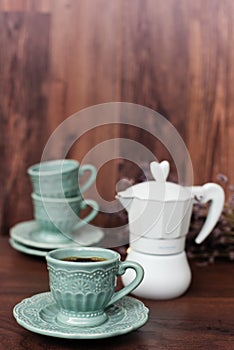 Cup of coffee and Italian coffee maker in blue, scent of lavender. Dark background