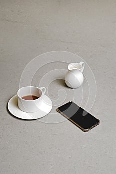 Cup of coffee, jar with cream and mobile smartphone