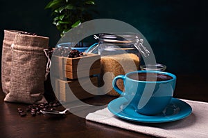 cup of coffee and jute bags, wooden container, cane sugar