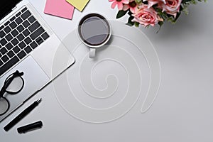 Cup of coffee, laptop computer, glasses and sticky notes on white table.