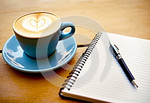 Cup of coffee with latte art on wooden table with notebook. Generative AI
