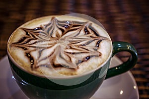 Cup of coffee latte with design art in froth, on a