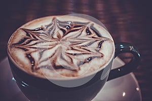 Cup of coffee latte with design art in froth, on a