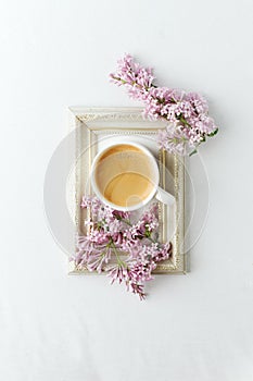 Cup of coffee, lilac branch and frame on white background. Flat lay, top view, copy space, wedding, female morning breakfast,