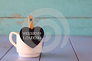 Cup of coffee and little heart shape chalkboard with the phrase: WEEKEND LOADING.