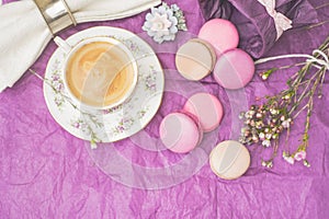 Cup of coffee with macaroons and decoration on the purple paper horizontal