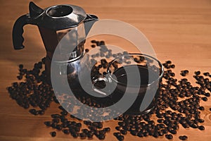 Cup of coffee and coffee maker moka pot with roasted coffee beans on wooden table.